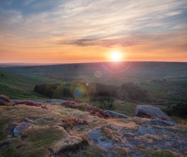 Stunning late Summer sunrise in Peak District over fields of heather in full bloom around Higger Tor and Burbage Edge