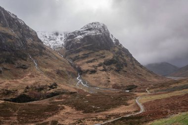 Glencoe İskoç dağlarında kar tepeli üç kız kardeşin dramatik gökyüzü eşliğinde destansı kış manzarası