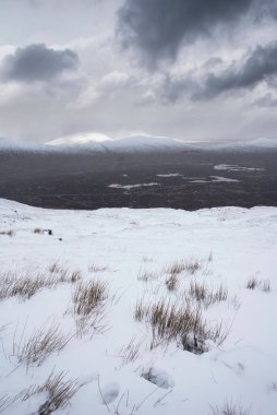 Kar fırtınası sırasında İskoçya 'nın dağlarının tepesinden Rannoch Moor' a kadar uzanan güzel kış manzarası ve yüksek rüzgarlarla dağların tepesinden kayma.
