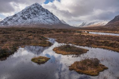 Önplanda Etive Nehri 'nin güzel kış manzarası. Arkaplanda ikonik kar örtülü Stob Dearg Buachaille Etive Mor dağı var.