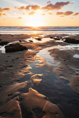 Devon İngiltere 'de Widemouth Körfezi' nin güzel yaz günbatımı manzarası. Sahilde altın saat ışığı var.