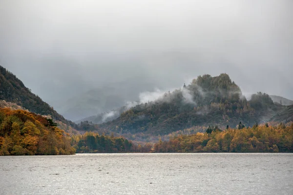 レイク地区のデルウェントウォーター沿いの秋の景色の中に霧に包まれた美しい風景のイメージ — ストック写真