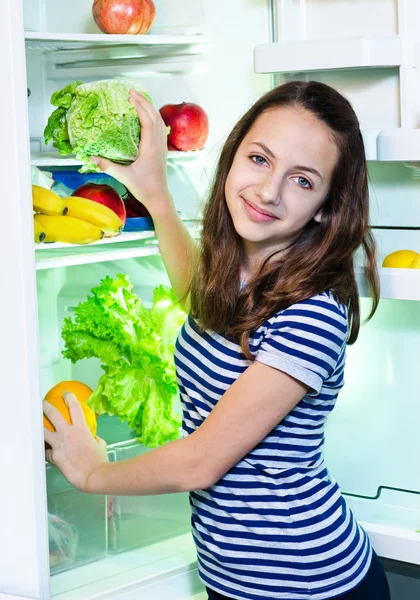 Hermosa chica joven cerca del refrigerador con comida saludable —  Fotos de Stock
