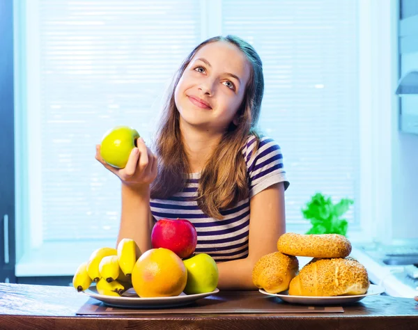 Healthy Food. Beautiful Young Woman choosing between Fruits and Sweets — Stock Photo, Image