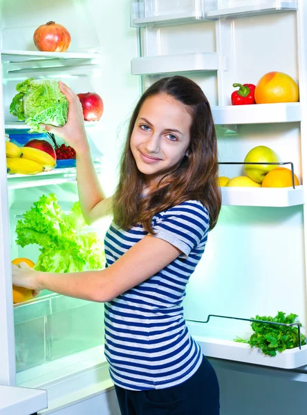 Hermosa chica joven cerca del refrigerador con comida saludable —  Fotos de Stock