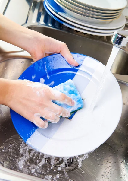 Mani ravvicinate di donna che lava i piatti in cucina — Foto Stock