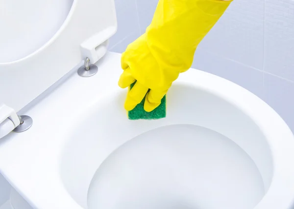 Mãos em luvas amarelas limpando um banheiro — Fotografia de Stock