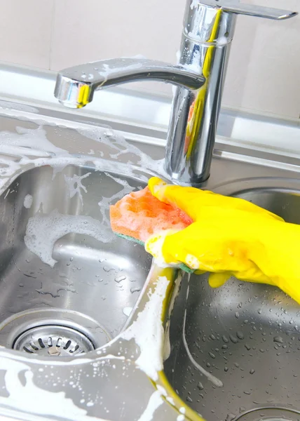 Person rengöring kök diskbänk med en handske — Stockfoto
