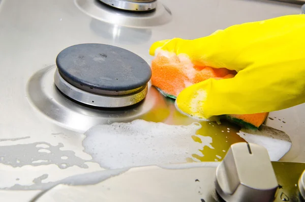 La mano della persona in un guanto di gomma pulisce un fornello a gas di cucina — Foto Stock