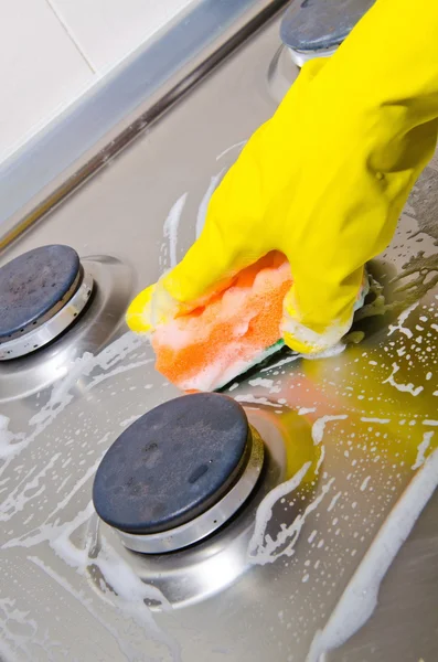 Рука человека в резиновой перчатке чистит кухонную газовую плиту — стоковое фото