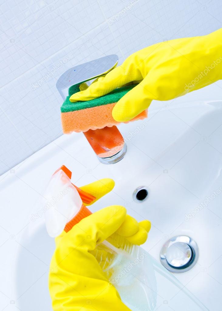 woman doing chores in bathroom at home, cleaning sink and faucet with spray detergent