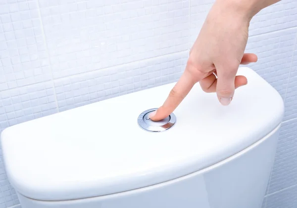 Doigt appuyant sur le bouton et chasse d'eau toilettes — Photo