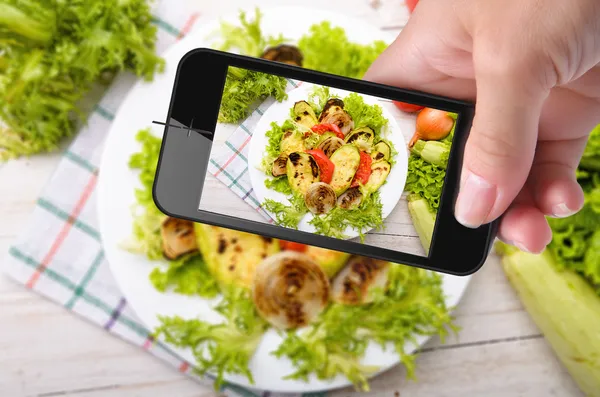 Mãos tirando fotos de vegetais grelhados com smartphone — Fotografia de Stock