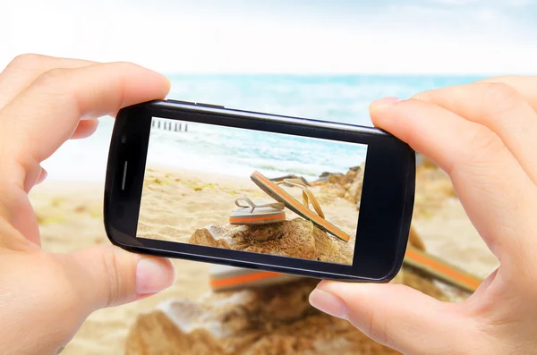 Händerna ta foto flip flops med smartphone — Stockfoto