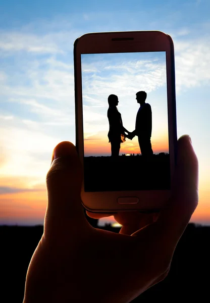 Ręce biorąc zdjęcie młodej pary w miłości z smartphone — Zdjęcie stockowe