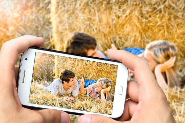 Ręce biorąc zdjęcie młodej pary w miłości z smartphone — Zdjęcie stockowe