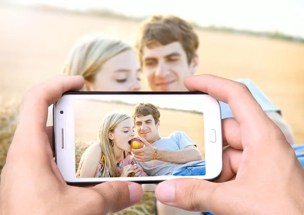 Ręce biorąc zdjęcie młodej pary w miłości z smartphone — Zdjęcie stockowe