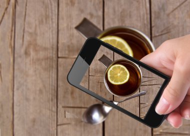Hands taking photo cup tea with smartphone clipart