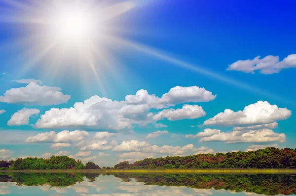 Sjön och sol på himlen bakom trä. — Stockfoto