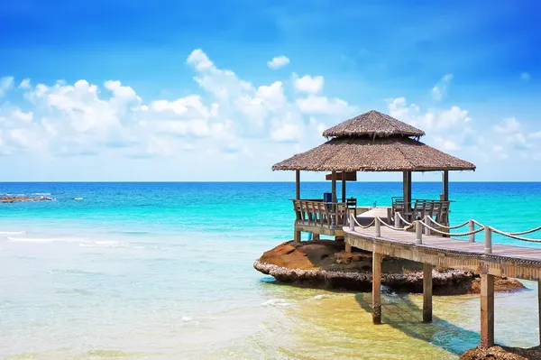 Mare con molo sotto cielo azzurro nuvoloso — Foto Stock