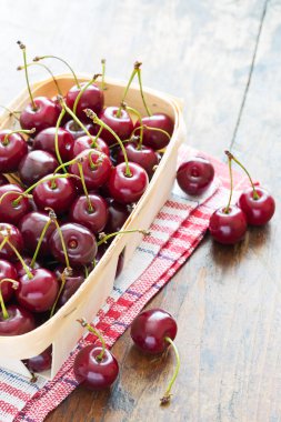 ahşap bir masa üzerinde bir kapta taze kırmızı kiraz
