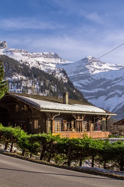 Carretera en los Alpes y cabañas de madera al margen — Foto de Stock