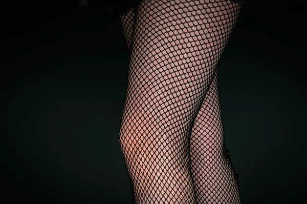 Pernas de uma mulher youn contra fundo escuro — Fotografia de Stock