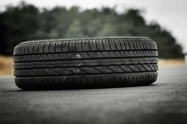 Opuštěné auto pneumatiky na silnici se zeleným pozadím — Stock fotografie