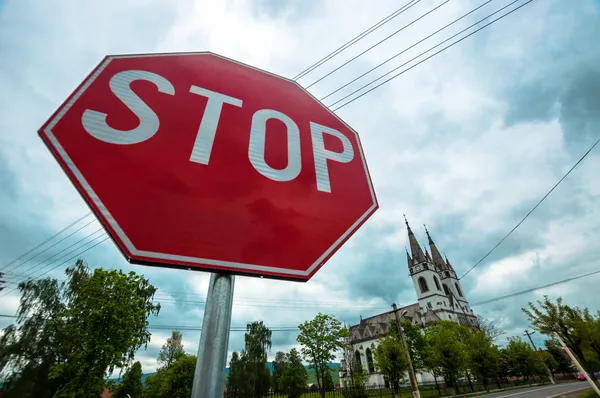 Segnale di stop rosso con chiesa sullo sfondo — Foto Stock