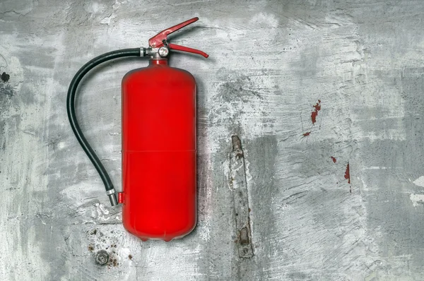 Red fire extinguisher on concrete wall — Stock Photo, Image