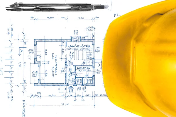 Casco amarillo de un ingeniero con planos — Foto de Stock