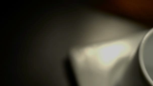 Белая чашка на тёмном столе — стоковое видео