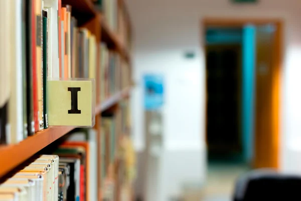 Bibliotheek boekenplank close-up met letter — Stockfoto