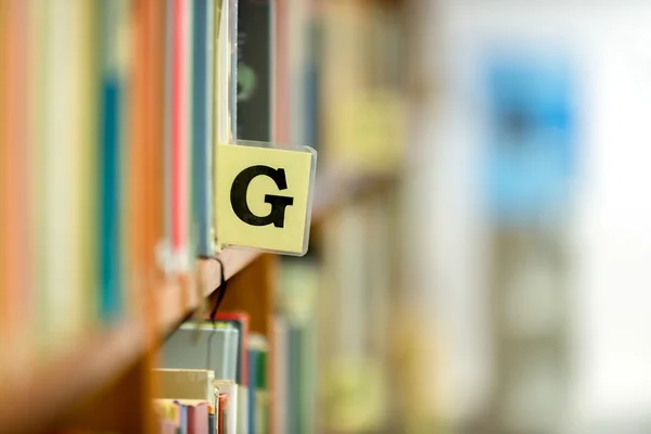 Bibliotheek boekenplank close-up met letter — Stockfoto