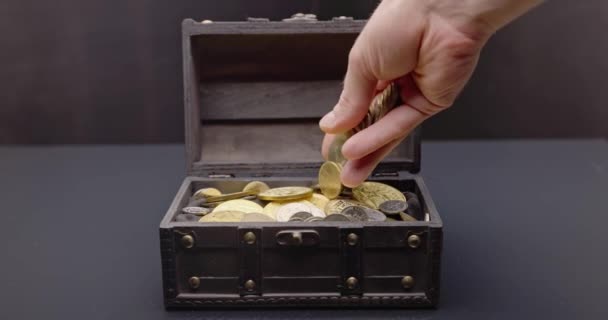 Mano poniendo monedas en el cofre del tesoro imágenes en cámara lenta — Vídeo de stock