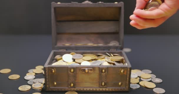 Mano poniendo monedas en el cofre del tesoro imágenes en cámara lenta — Vídeo de stock