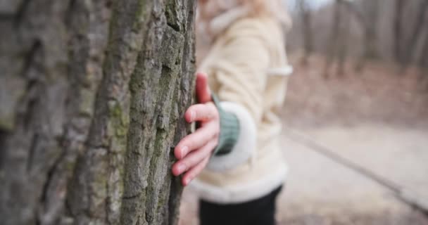Женщина касается и гладит корой дерева с камерой после замедленного движения — стоковое видео