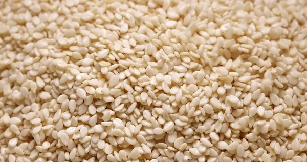 Zbliżenie zdjęcie naturalnych suszonych nasion sezamu białego płynących — Zdjęcie stockowe
