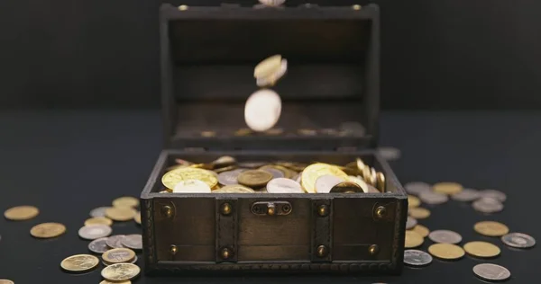 Money falling into treasure chest in slow motion closeup