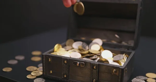 Money falling into treasure chest in slow motion closeup