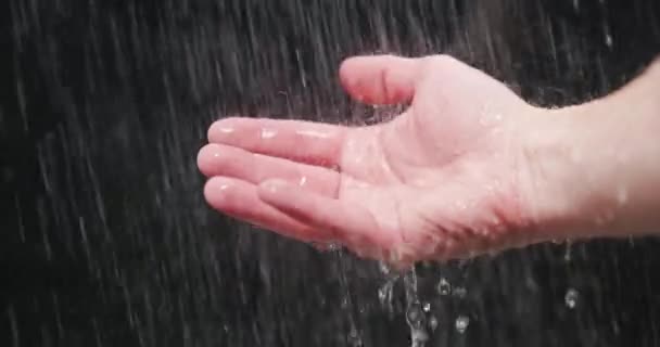 Água caindo nas palmas das mãos contra fundo escuro — Vídeo de Stock