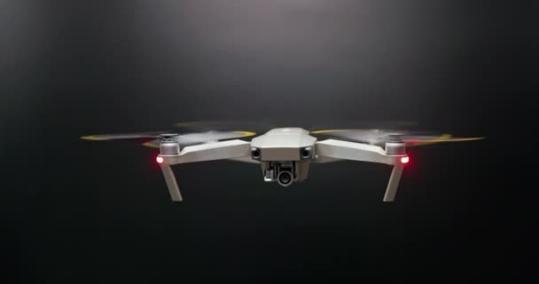Small drone flying against dark background — Vídeos de Stock
