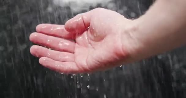 Woda padająca na dłonie na ciemnym tle — Wideo stockowe