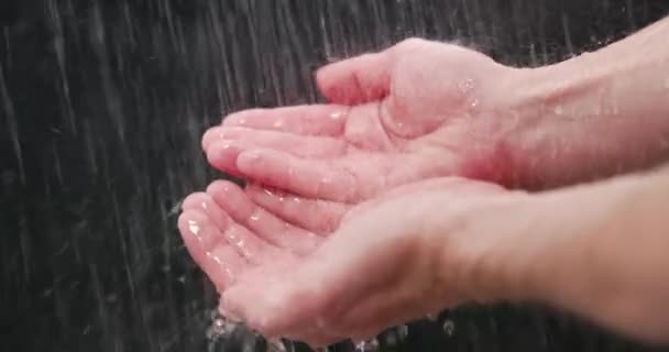 Woda padająca na dłonie na ciemnym tle — Wideo stockowe