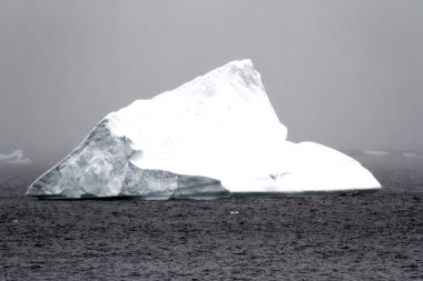 Antarctica - Non Tabular Iceberg Drifting In The Ocean - Antarctica In A Cloudy Day. Global warming clipart