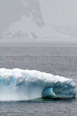 Antarktika - Okyanusta sürüklenen Tablo Olmayan Buzdağı - Bulutlu bir günde Antarktika. Küresel sıcaklık