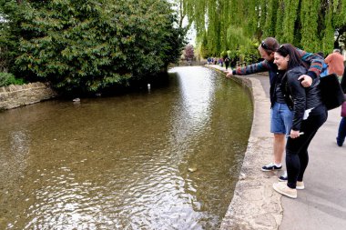 Genç çift, İngiltere 'nin Gloucestershire kentinde Cotswold köyü Bourton' da, Windrush Nehri 'nin nehir kenarının tadını çıkarıyor. 25 Mayıs 2015