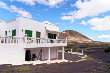 Mancha Blanca 'nın Lanzarote adasındaki tipik Kanarya beyaz çiftlik evi. Güneşli bir kış öğleden sonrasında arka planda volkan kraterleri var. Lanzarote Adası, Kanarya Adaları, İspanya