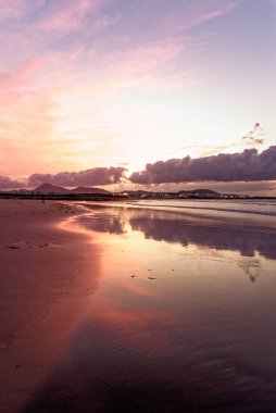 Famara Sahili 'nde günbatımı. Lanzarote Kanarya Adaları Caleta de Famara, Famara Sahili Rüzgar sörfü ve akşam güneşinde sörf plajı.