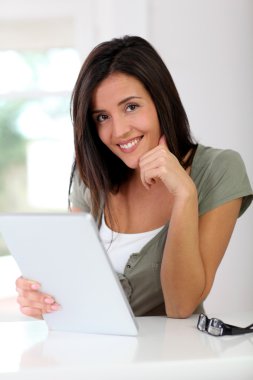 evde elektronik tablet üzerinde çalışan genç kadın gülümsüyor